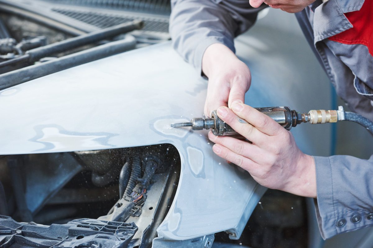 Auto body repairs. Repairman mechanic worker working with automobile car body in garage workshop